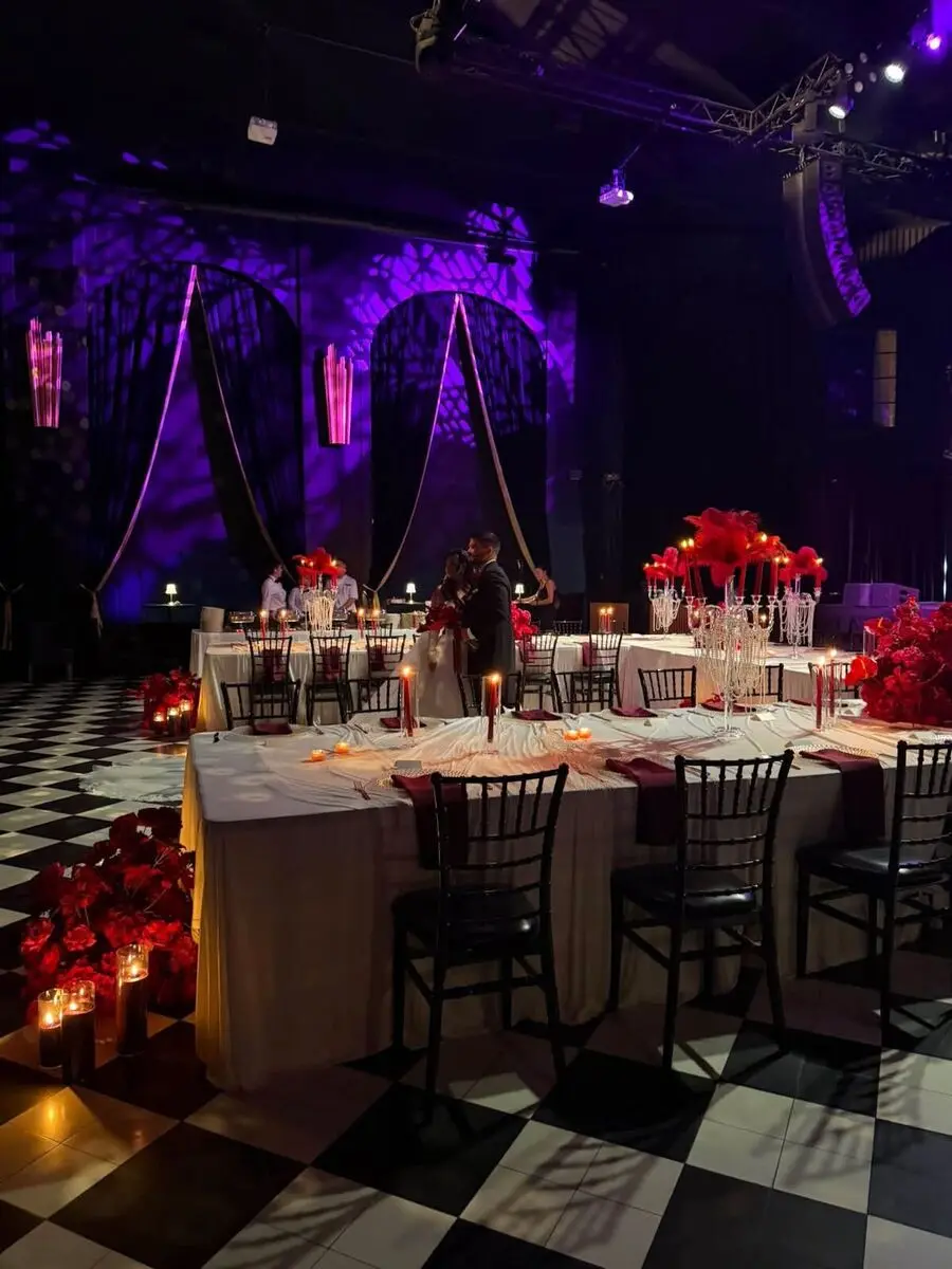 Reception tables with red feathered candelabras and purple uplighting at a luxury gala.